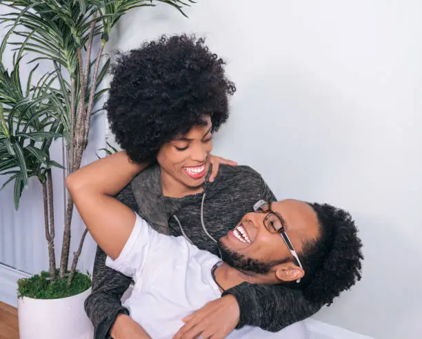 Closeup portrait of couple hugging and smiling young happy husband and wife with Afro hair style at home.