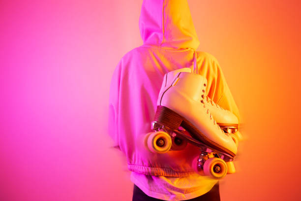 adolescente carregando patins clássicos de couro em fundo rosa e laranja - patinagem - fotografias e filmes do acervo