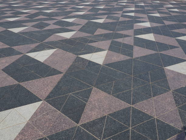 istock The square is paved with triangular tiles. Grey, white, black tiles on the street. The cobblestone surface. Modern design of streets, avenues, squares, shopping centers. Wear-resistant flooring. 1383174548