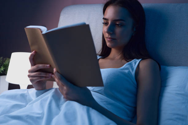 istock Woman reading book in bed 1383177055