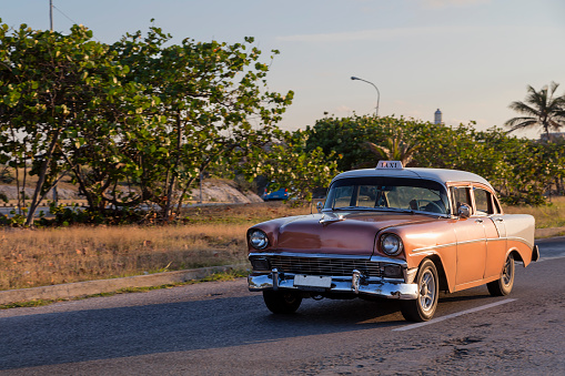 Vintage American car driving along Gulf of Mexico coast towards Havana, Cuba