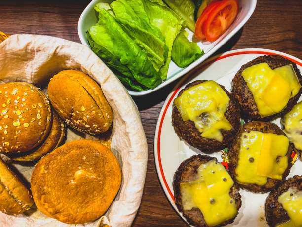 Bread, salad, cucumbers, tomatoes and meat with bread for cheeseburgers.