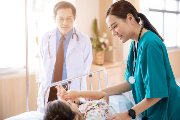 Pediatrician visiting parents and child in hospital bed ward stock photo