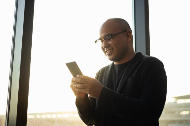 istock Smart Asian man using mobile phone to social media with beautiful sunlight. Businessman using cell phone for business communication in airport. Smartphone concept. 1383205619
