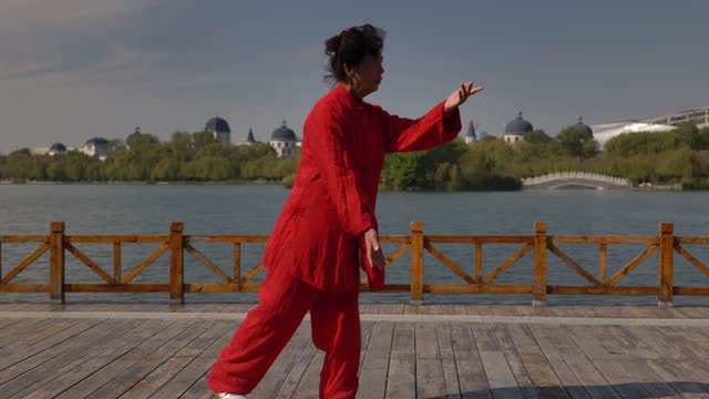 A woman is practicing Taijiquan by the lake.