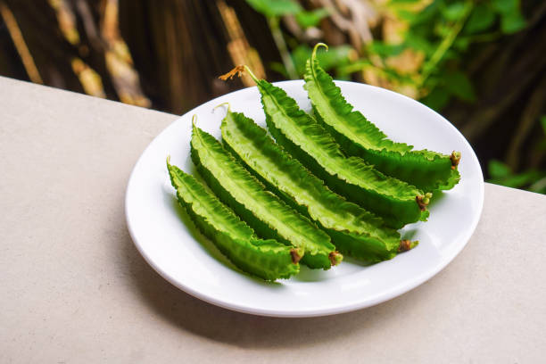 istock fresh five winged bea vegetables on white dish on white floor background, vegetable, health, copy space 1383225075