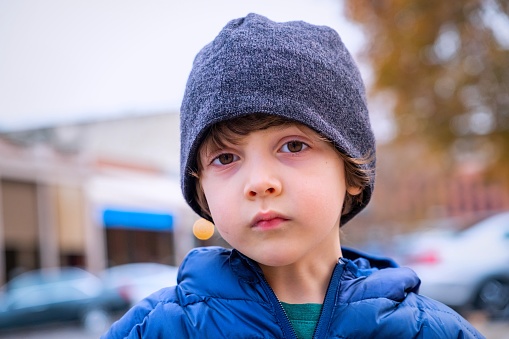 Serious pensive caucasian little boy looking at the camera wearing a toque hat