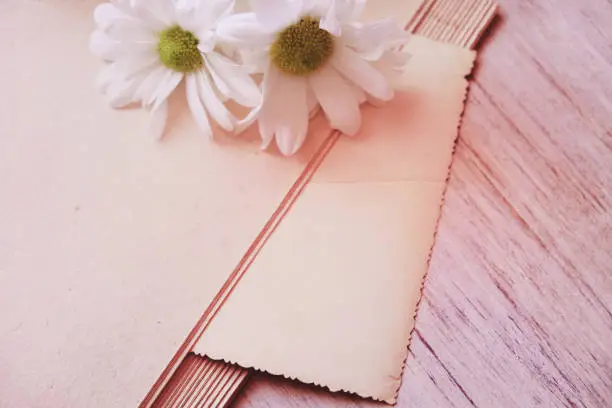 Photo of Empty page vintage book and summer flowers on wooden table.  Love concept. Bouquet of chamomiles . Vintage effect