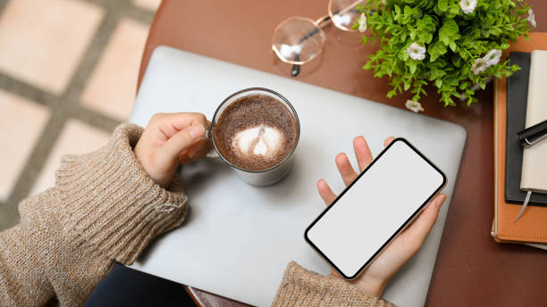 Top view, Relaxed woman holding smartphone and coffee cup Top view, Relaxed woman in knitted sweater holding smartphone and coffee cup over her coffee table. coffee table top stock pictures, royalty-free photos & images