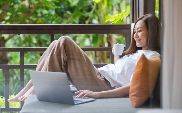 istock Portrait image of a young woman using laptop computer for working or studying online while drinking coffee and laying on sofa at home 1383246307