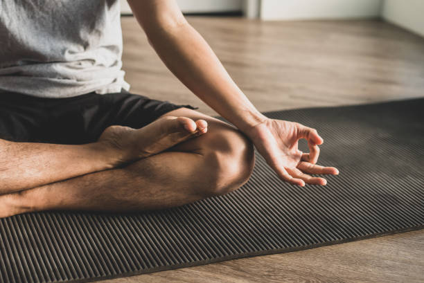 istock Young man sitting on the exercise mat practicing meditation in a lotus pose alone at the gym in the morning. He was closing his eyes, slowly breathing in and out. 1383272145