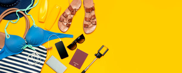 Female summer clothing accessories on yellow background. Concept of travel vacation sea. Hat swimming suit denim shorts leather sandals sunglasses sunscreen sea bag passport phone. Flat lay top view. accesorios de ropa femenina de verano sobre fondo amarillo. concepto de viaje de vacaciones en el mar. sombrero traje de baño pantalones cortos de mezclilla sandalias de cuero gafas de sol protector solar bolsa de mar pasaporte teléfono. vista plana de l