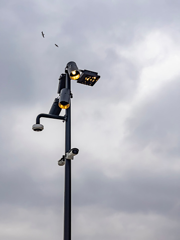 Surveillance cameras on the street. Group of technology items against sky background with copy space. Watching cameras and electrical light on a pole in the city. Security CCTV camera in a city