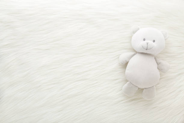 Smiling baby teddy bear on white fluffy fur blanket background. Closeup. Empty place for inspiration, emotional, sentimental text, quote or sayings. Top down view. stock photo