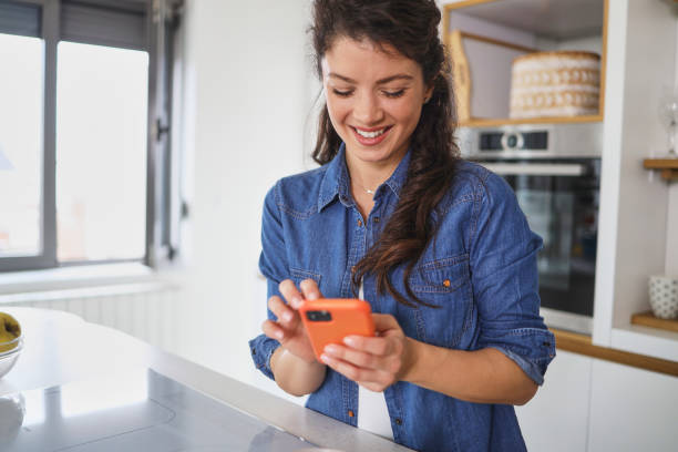 istock Smiling mature woman messaging while standing at her kitchen in the morning 1383326246