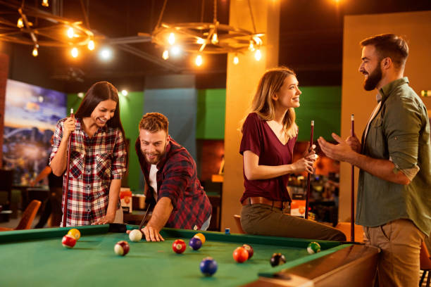 istock Group of friends having fun while playing pool in a local pool hall 1383334381