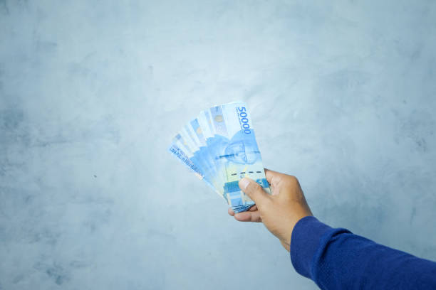 istock A man holding and showing rupiah banknotes 1383348311