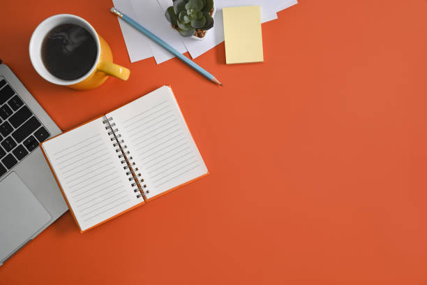 istock Notebook, laptop computer and coffee cup on orange background. Top view. 1383358943