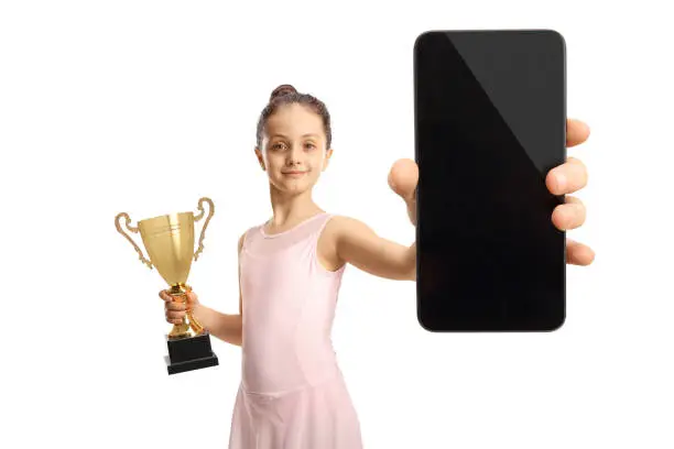 Photo of Ballerina in a pink dress holding a gold trophy cup and a smartphone