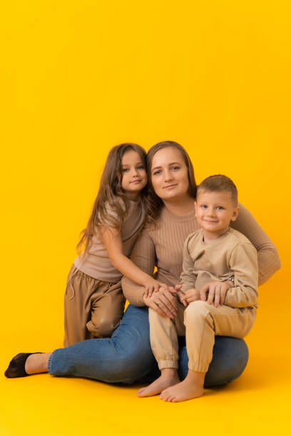 istock A young mother with her daughter and son in a studio on a yellow background 1383373219