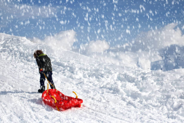 kleiner junge zieht schneeschlitten auf verschneitem berg - little boys sled clothing slide stock-fotos und bilder