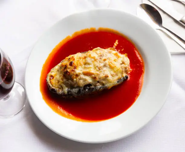 Photo of Plate with baked stuffed eggplant with a cheese crust on top in tomato sauce