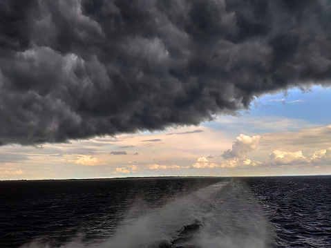 Summer day at sea with drastic weather change. Black storm and rain clouds come tumbling towards us