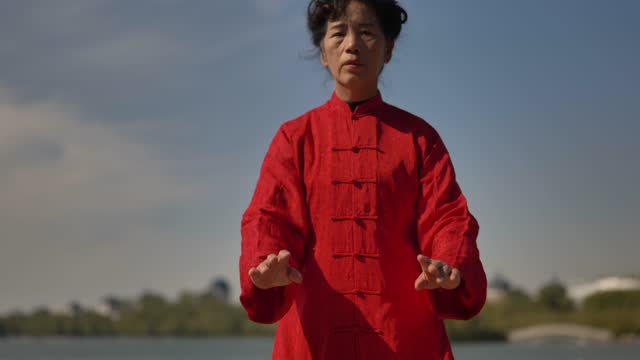 A woman is practicing Taijiquan by the lake.