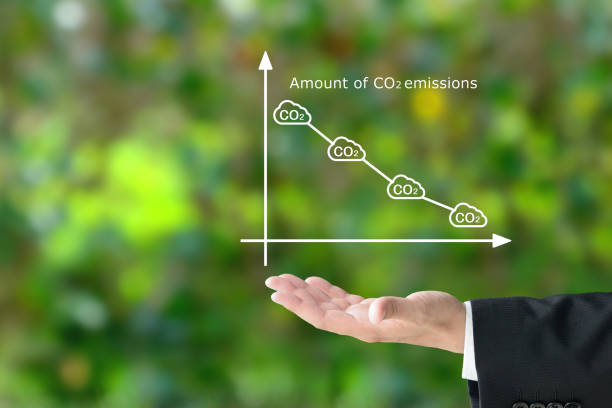 mano dell'uomo d'affari che aumenta il grafico di tendenza al ribasso per la quantità di emissioni di co2 sul backgorund verde naturale - green cross foto e immagini stock