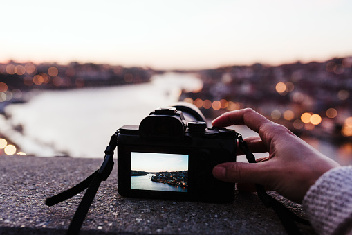 close up of woman in Porto bridge taking pictures with camera at sunset. Tourism in city Europe