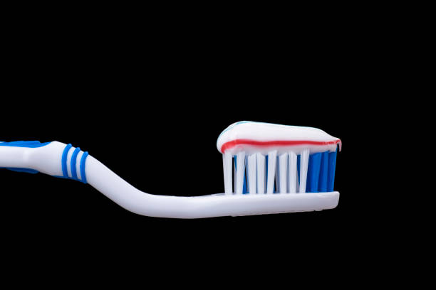 Two old toothbrushes and an old toothpaste lie on a shelf in the bathroom.