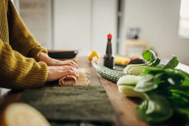 One woman, modern Japanese female preparing sushi in kitchen at home.