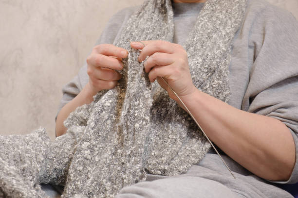 frau mittleren alters strickt einen grauen wollschal - threaded indoors inside of pattern stock-fotos und bilder