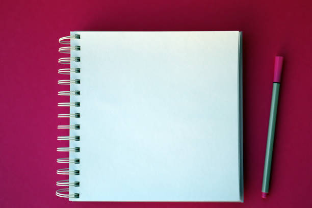 istock Mockup planner flat lay, top horizontal view pink background. White notepad with pen. 1383393704