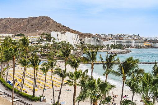 Clean beach with beach beds in front of calm water of the sea. Famous Anfi beach in the south of Gran Canaria.