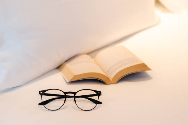 istock Spectacles puts near book on white bed sheet 1383397138
