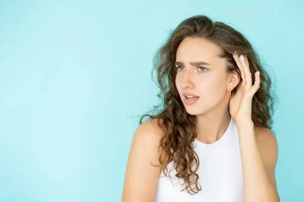 Hear gossip. Curious woman. Secrets spreading. Pretty lady holding hand over ear waiting for interesting information isolated blue copy space.