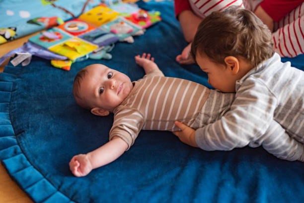 Two boys playing beside the bed.