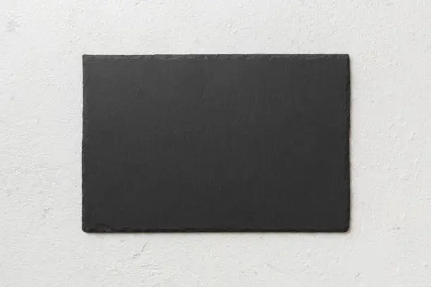 Photo of top view of empty black slate plate on cement background. Empty space for your design