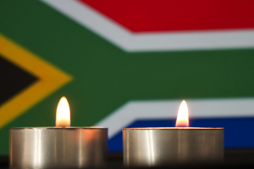 Energy crisis in South Africa. Concept image of candles burning in front of the South African flag. Eskom the power utility implementation of rolling blackouts or loadshedding due to reduced energy output and to reduce the risk of total grid failure.
