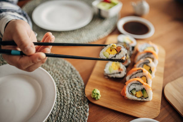 Homemade sushi for lunch One man, man having homemade sushi for lunch in dining room at home. maki sushi stock pictures, royalty-free photos & images