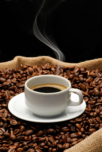 Taza de café y humo sobre granos de café tostados photo