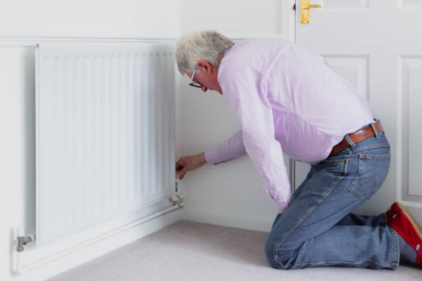 istock Senior man adjusting heat on radiator - reducing energy consumption 1383421163