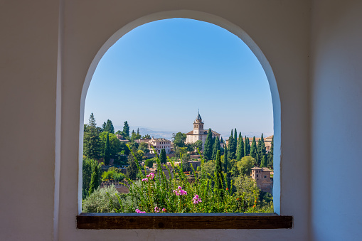 The alhambra through the arched window from the generalife gardens in granada, spain