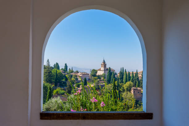 The alhambra through the arched window from the generalife gardens in granada, spain stock photo
