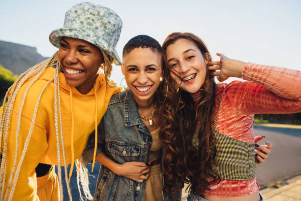 istock Female friends smiling while embracing each other outdoors 1383424973