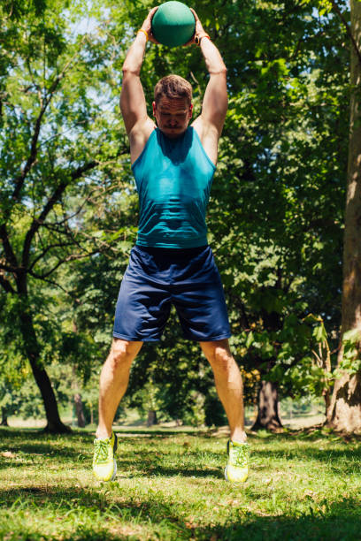 istock Athletic guy doing workout with medicine ball in the park 1383431687