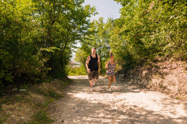 istock Athletic couple running together on forest trail 1383434965