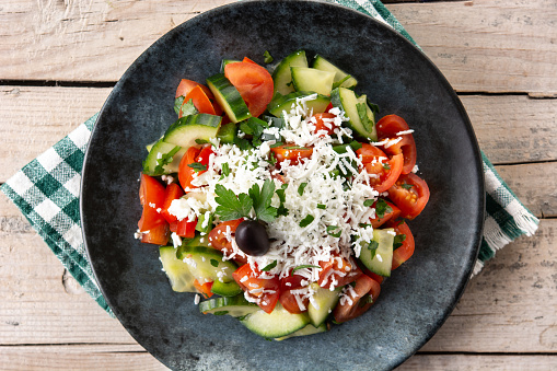 Traditional Bulgarian shopska salad with tomato,cucumber and bulgarian sirene cheese on wooden table