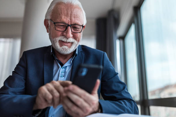 istock Senior businessman checking using mobile smart phone in modern office 1383439328